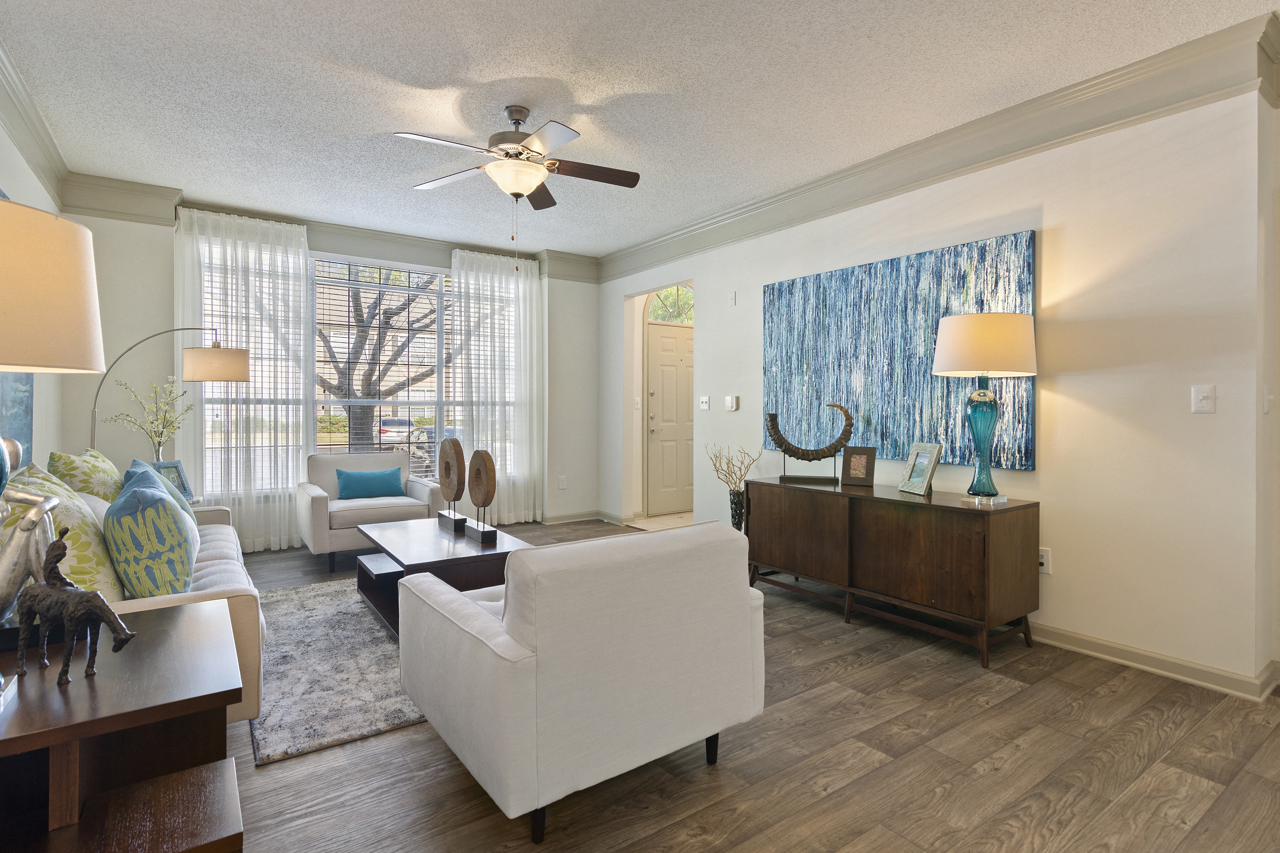 a living room with white furniture and a ceiling fan